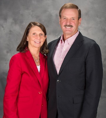 A photograph of a man in a sportsjacket and a woman in a red blazer smiling