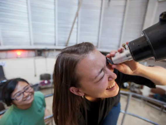 smiling looking through telescope