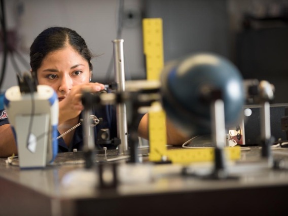A photograph of a woman working in an optics lab