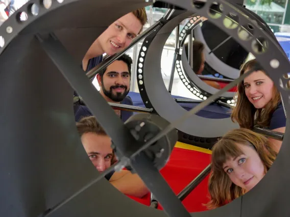 A photograph of Dr. Vishnu Reddy's Design Day team posing with one of two telescopes they designed.