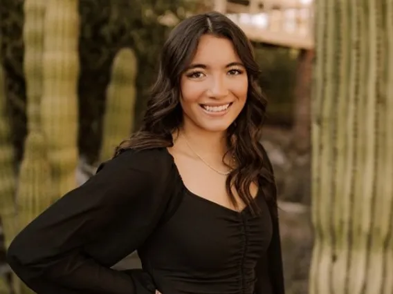 Maddy Hernandez in a black shirt and jeans smiling in front of Old Main