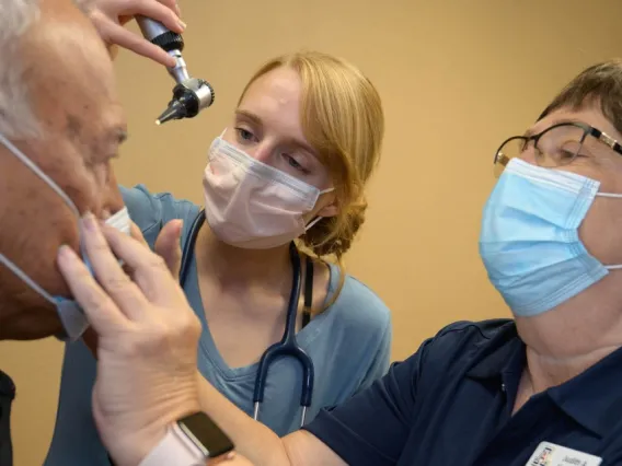 Two health professionals using a light to look in a patient's eyes