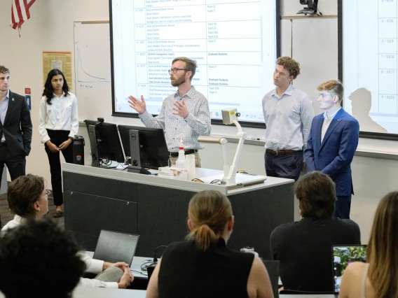 Eller students and staff member standing in front of a class lecturing 