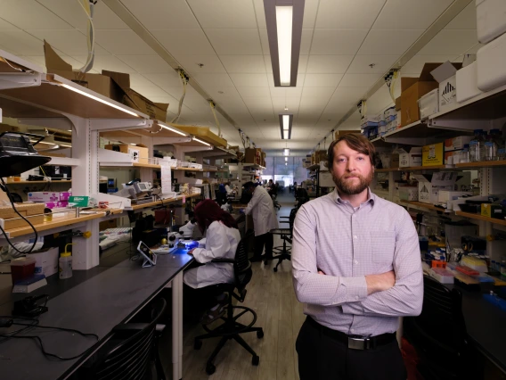 An Image of Phillipp Gutruf, standing facing the camera with his arms crossed, in the Gutruf Lab where biomedical sensors for inside and outside the body. are developed.