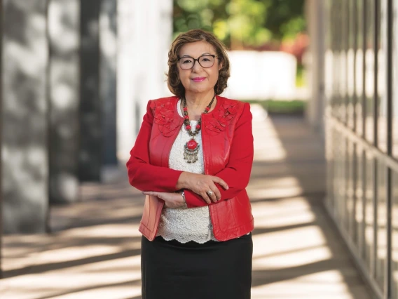 A woman standing in a bright red jacket with her arms crossed.