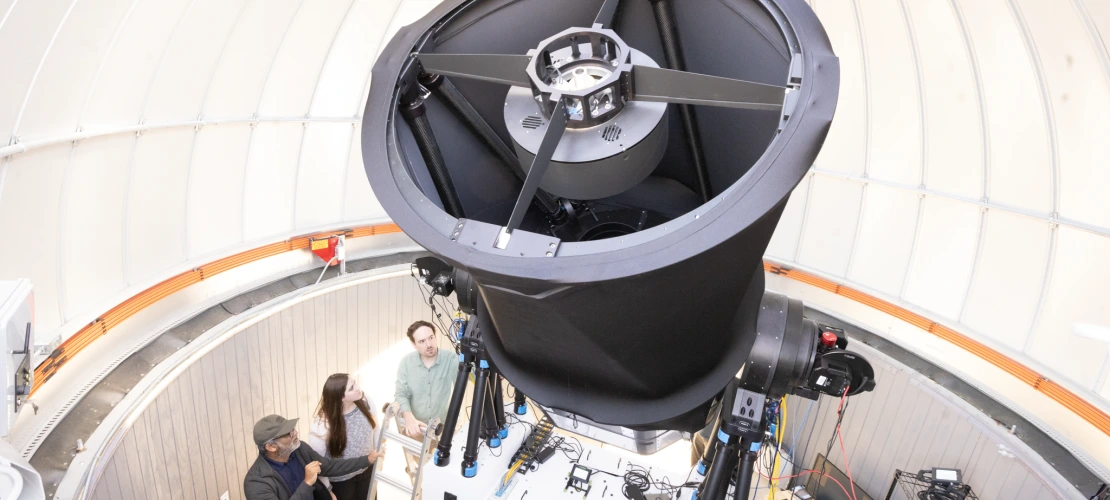 Three people are talking while looking at a new instrument 