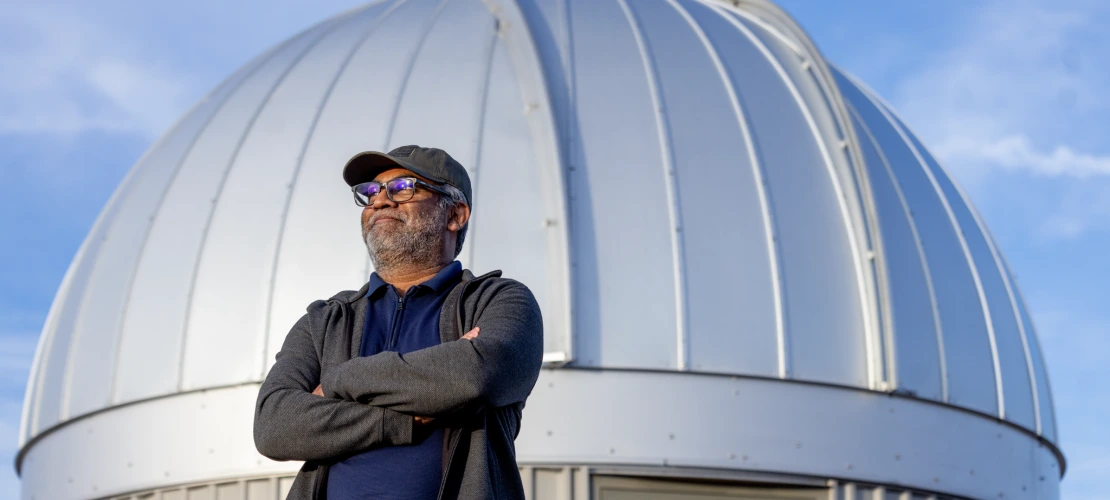 A man standing with his arms crossed in front of a white dome 