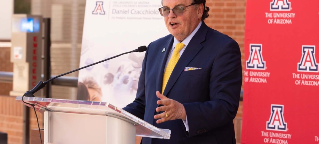 A man addressing a group while speaking in front of a College of Medicine podium