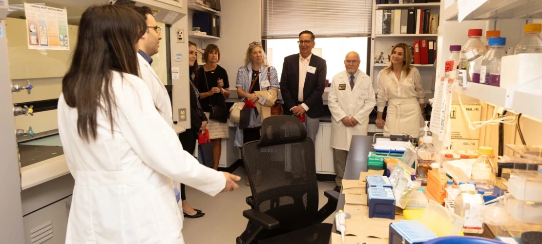 A group of people speaking to two researchers in a lab 