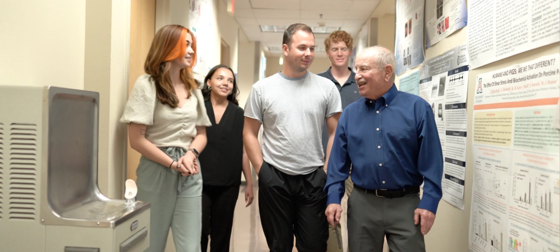Four students talking and walking in a hallway with Dr. Steven Goldman