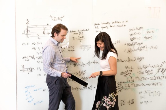 man and woman in front of a whiteboard with lots of equations 