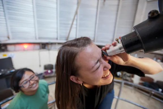 smiling looking through telescope