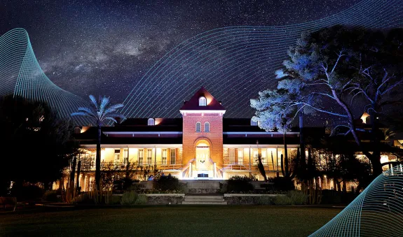 A photograph of Old Main at night with digital lines surrounding it