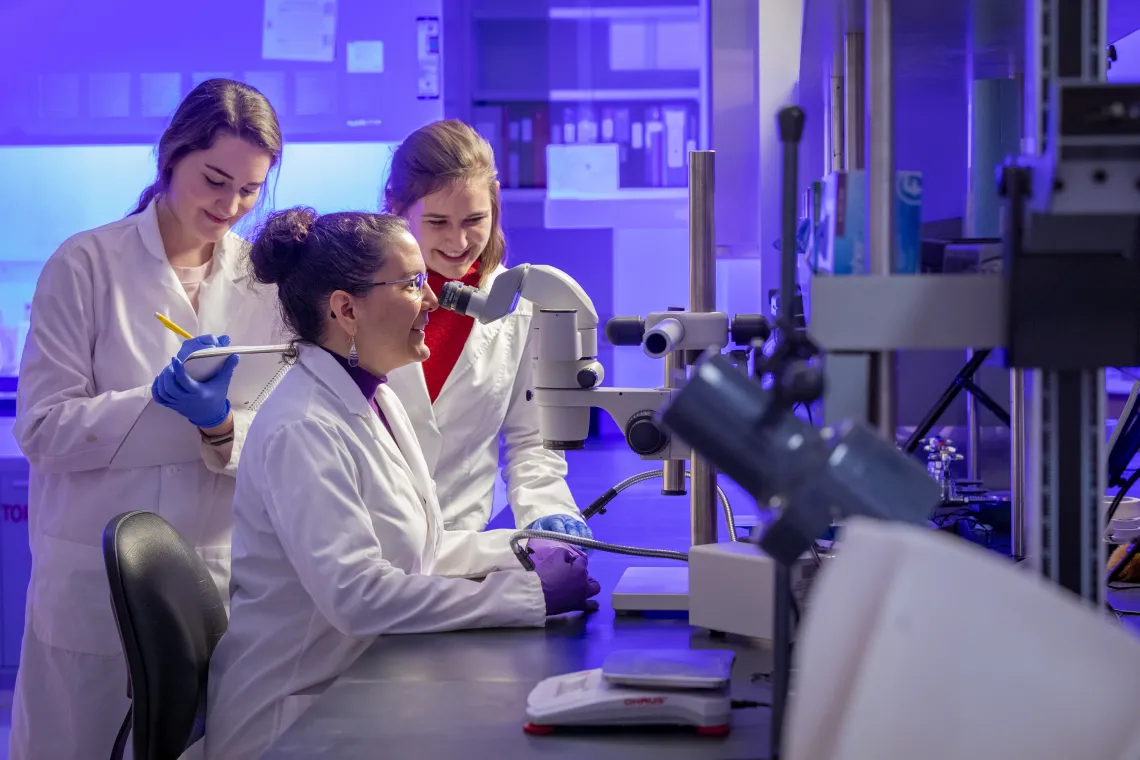 Student and faculty viewing through microscope in lab