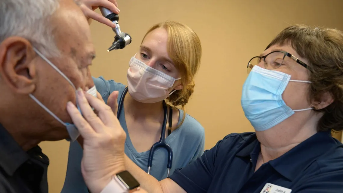 Two health professionals using a light to look in a patient's eyes