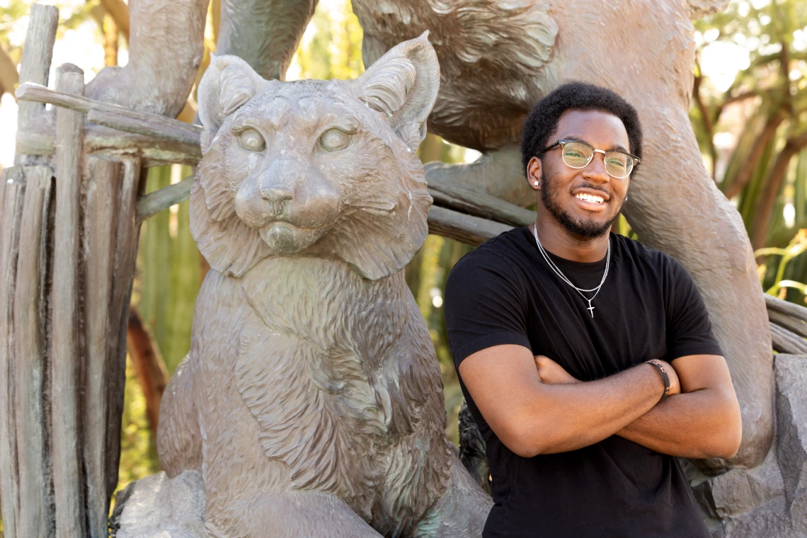 Daryl Ijaola standing next to the Wildcat statue