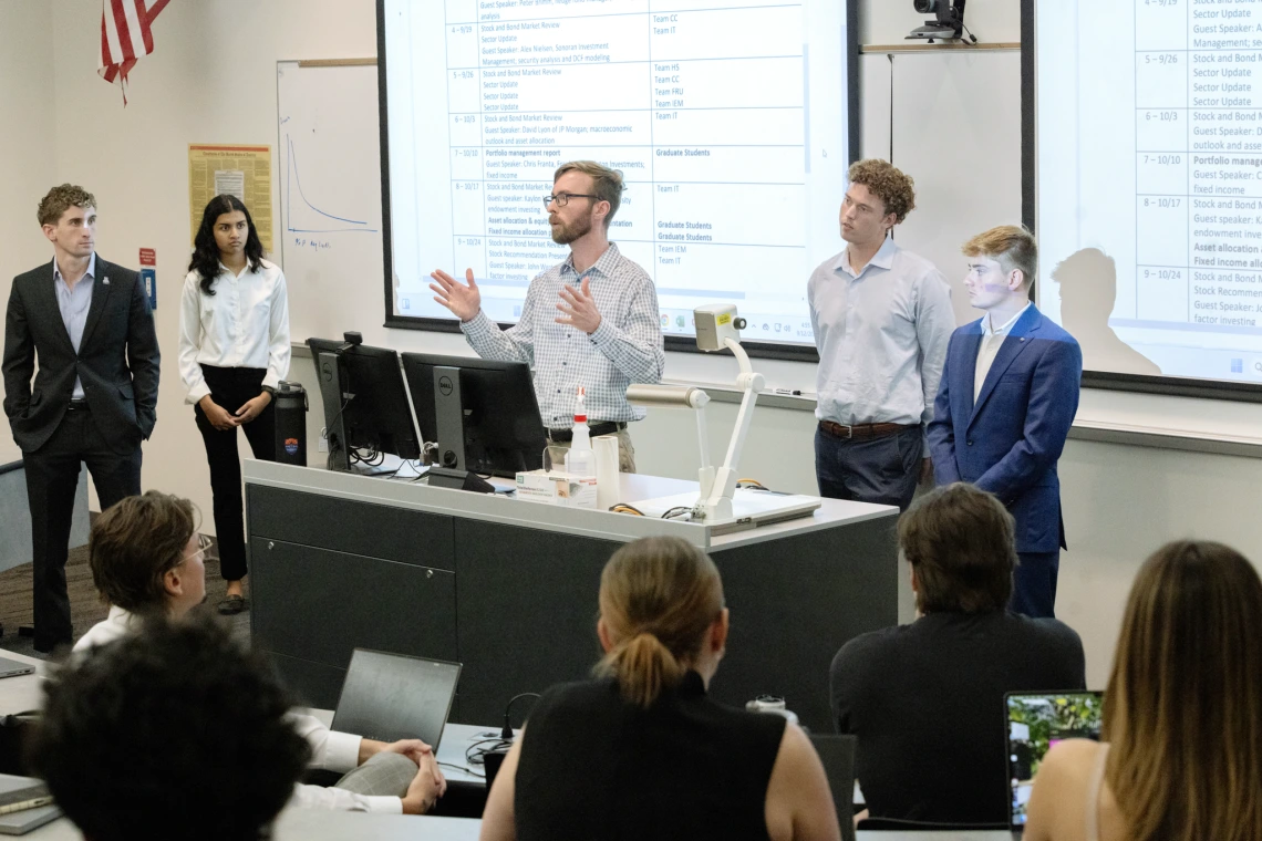 Eller students and staff member standing in front of a class lecturing 