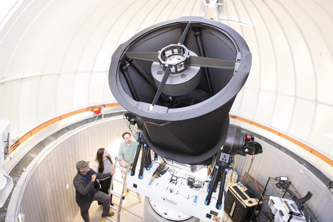 Three people are talking while looking at a new instrument 