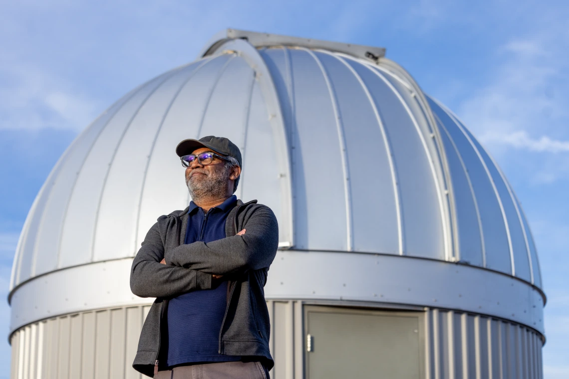 A man standing with his arms crossed in front of a white dome 