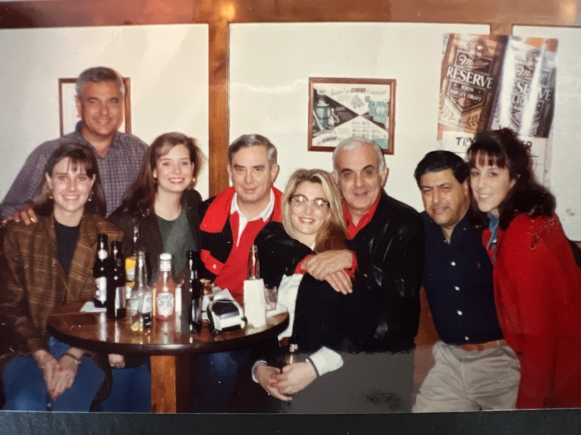 Eight people smiling and hugging at a bar.