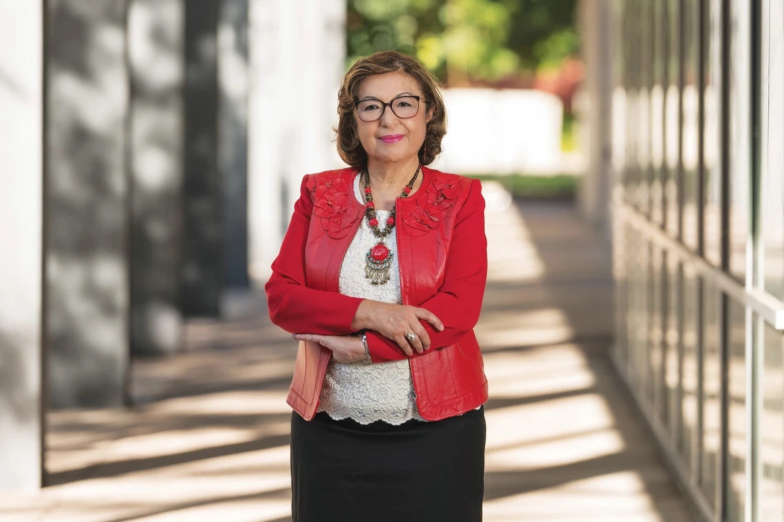 A woman standing in a bright red jacket with her arms crossed.
