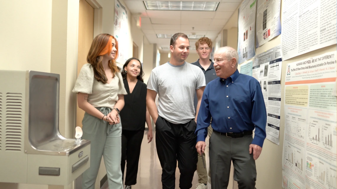 Four students talking and walking in a hallway with Dr. Steven Goldman