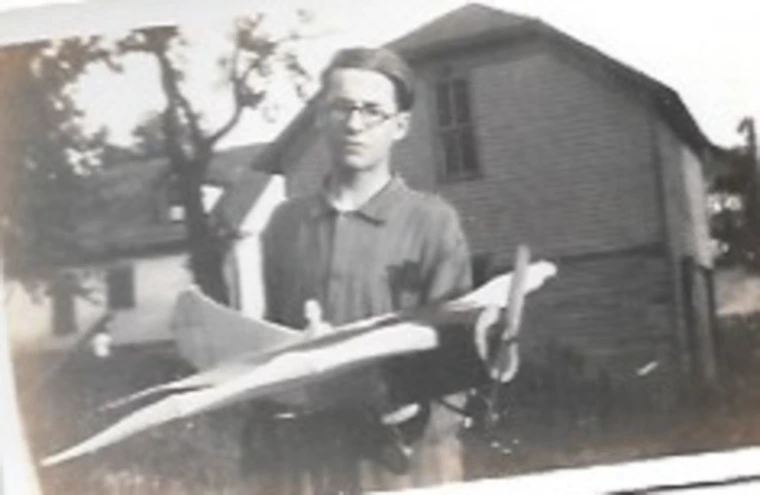 A black and white photo of a boy holding an airplane