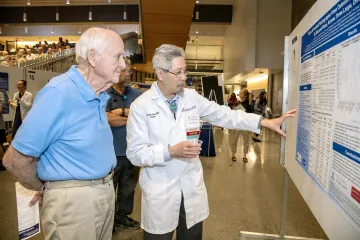 C. Kent Kwoh educates community participants, including Warren Wood, on arthritis and its many forms at the UAAC’s “Meet the Researchers” poster tour and presentation.