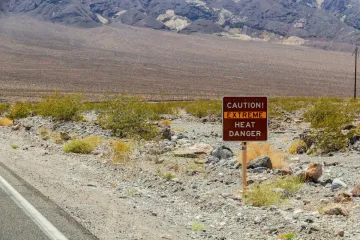 A rural road with a sign that reads "Caution Extreme Heat Danger"