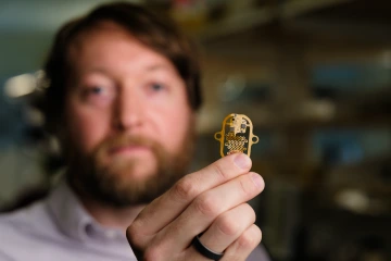 Phillipp Gutruf holding up a biomedical sensor that was made in the Gutruf Lab.