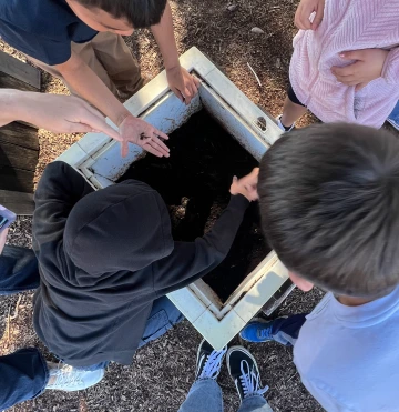 Children digging through dirt and holding worms