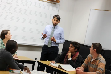 An image of Matthew Mugmon addressing students in a small group in a classroom.