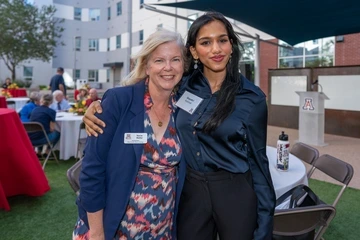 A woman smiling with a student's arm wrapped around her. 